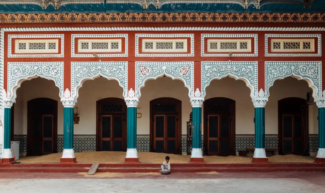 Een jonge jongen zittend voor een rijk versierd gebouw in Faisalabad, Punjab, Pakistan
